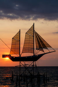 Silhouette sailboat on sea against sky during sunset