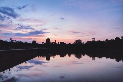 Reflection of silhouette trees in lake against sky during sunset