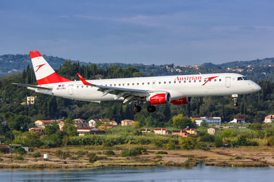 Airplane flying over river against sky