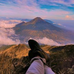 Low section of person on mountain against sky