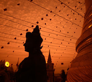 Buddha statue at temple against sky during sunset
