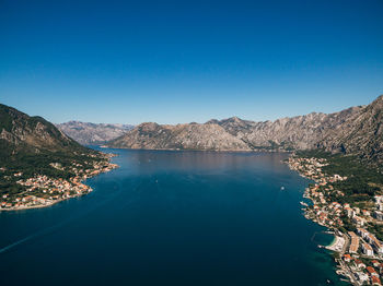 Scenic view of lake and mountains against clear blue sky