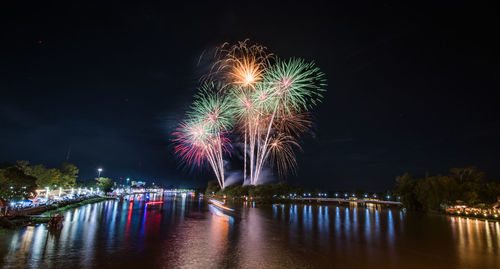 Firework display over river against sky at night