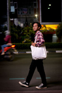 Side view of woman standing on road at night