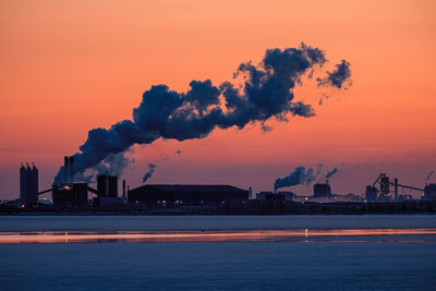 Smoke emitting from chimney against sky at sunset