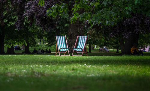 Two unoccupied deckchairs in the sunlight in a public park in london