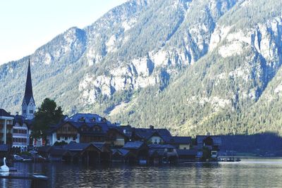 Scenic view of lake by buildings and mountains against sky