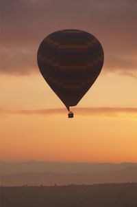 Hot air balloon flying over landscape against sky during sunset