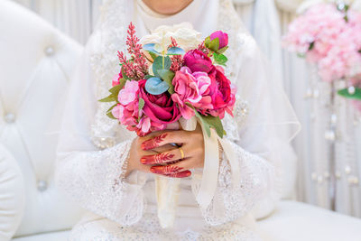 Midsection of bride holding flower bouquet