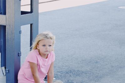 High angle view of cute girl looking away while standing by metal on road