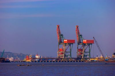 Cranes at commercial dock against sky