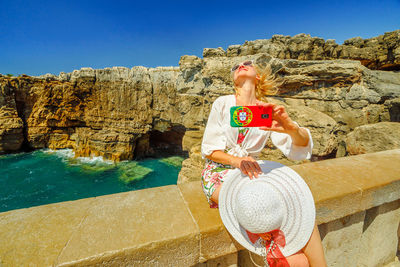 Woman taking selfie through mobile phone at beach