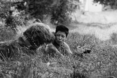 Woman playing with dog on grassy field