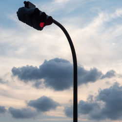 Low angle view of road signal against cloudy sky during sunset