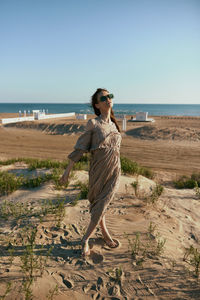 Young woman standing at beach against clear sky