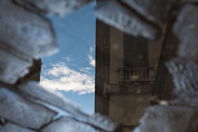 Reflection of building and sky in puddle on street