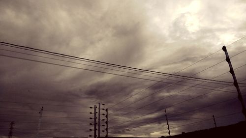 Low angle view of silhouette electricity pylon against sky