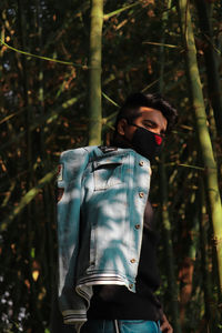 Young man wearing mask standing in forest