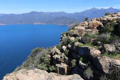 High angle view of rocks and sea against blue sky