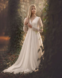 Full length of beautiful bride standing in forest