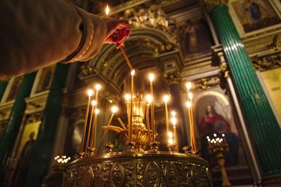 Low angle view of hand burning candle in cathedral during christmas