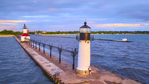 Lighthouse by sea against sky