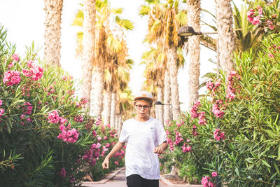 Portrait of young man standing by flowering plants