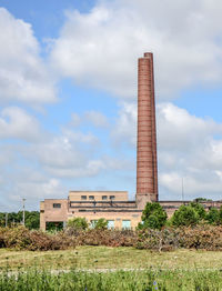 Factory on field against sky