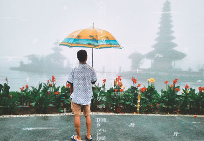 Rear view of woman standing on water during rainy season