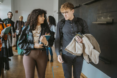 Young multiracial students discussing while walking in university