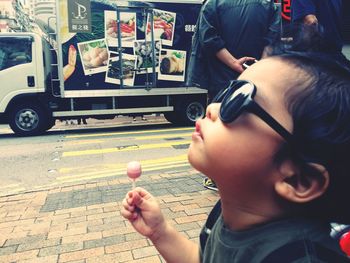 Close-up of cute boy holding lollipop in city