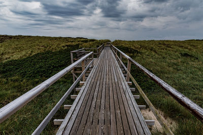 Boardwalk amidst landscape against sky