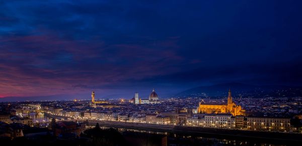 Illuminated cityscape against sky at dusk