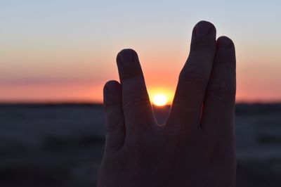 Optical illusion of sun seen through hand at sunset