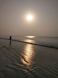 Silhouette person on sea against sky during sunset