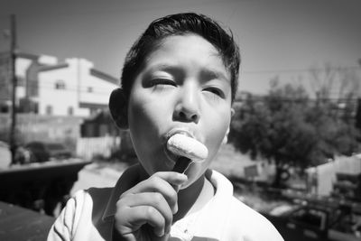 Close-up of boy eating popsicle while standing in city
