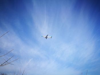 Low angle view of airplane flying against blue sky