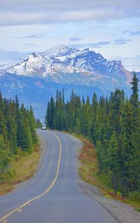 Road amidst snowcapped mountains against sky