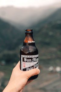 Close-up of hand holding bottle against blurred background