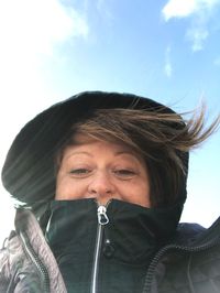 Low angle portrait of mature woman wearing warm clothing against sky during sunny day