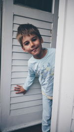 Portrait of boy smiling while standing at doorway