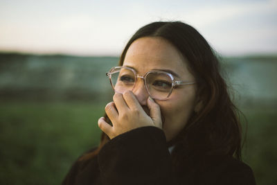 Portrait of young woman looking away against sky