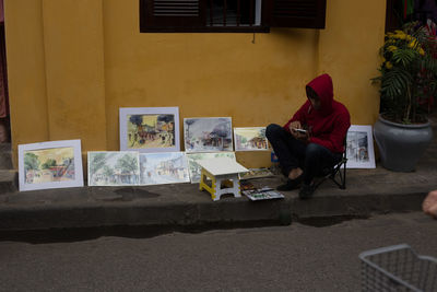 Man selling paintings on sidewalk