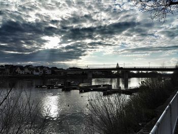 Bridge over river against cloudy sky