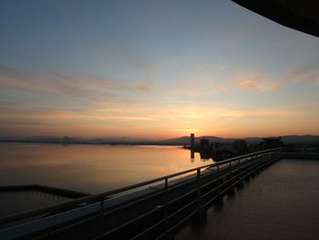 Man standing on bridge against sky during sunset