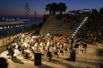 Crowd at music concert against sky at night