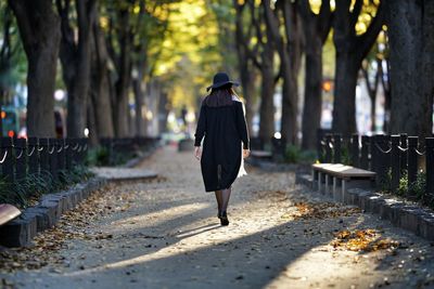 Rear view of woman walking on footpath during autumn