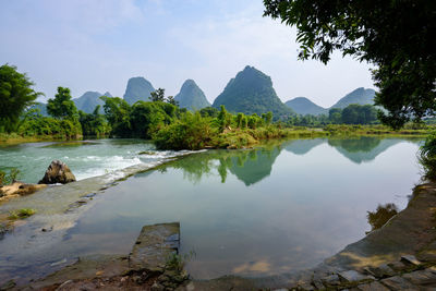 Scenic view of lake by trees against sky
