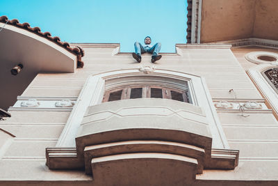 Low angle view of man sitting on building