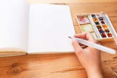 Midsection of person holding book on table